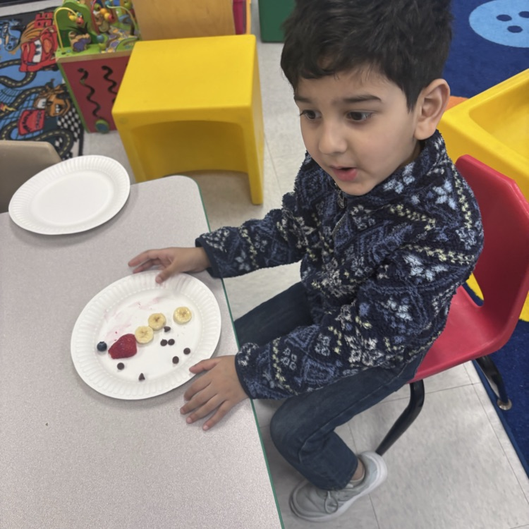 student sitting at table with fruit that looks like a snowman 