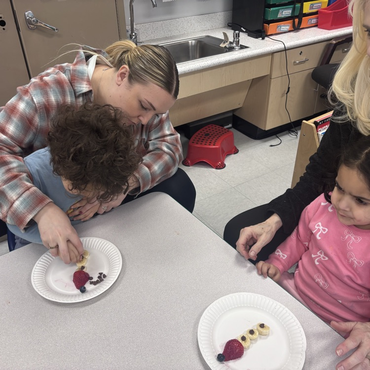 two students sitting at table with fruit that looks like a snowman 