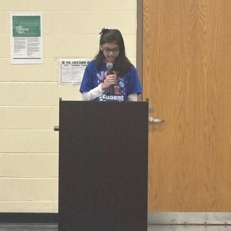 student speaking into a microphone behind a podium