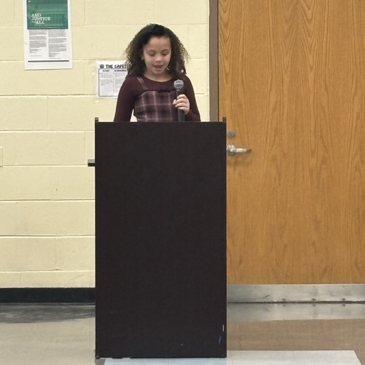 student speaking into a microphone behind a podium