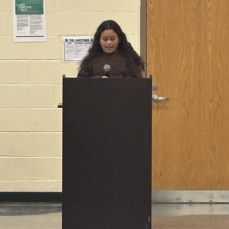 student speaking into a microphone behind a podium