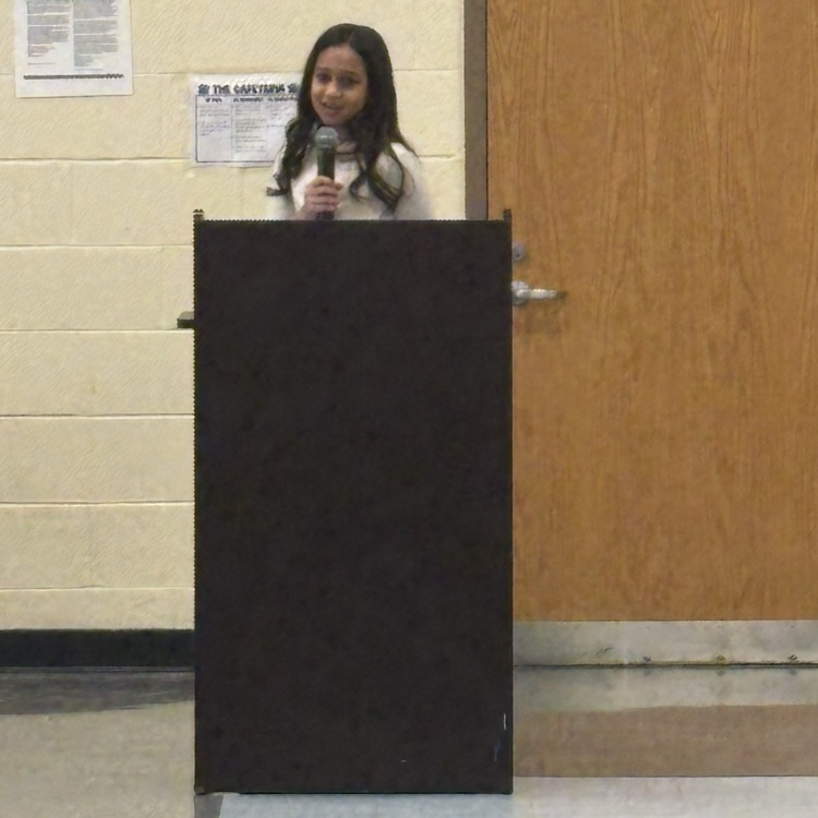 student speaking into a microphone behind a podium
