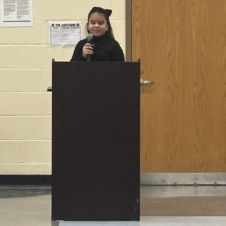 student speaking into a microphone behind a podium