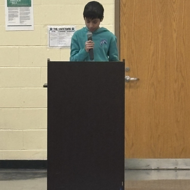 student speaking into a microphone behind a podium