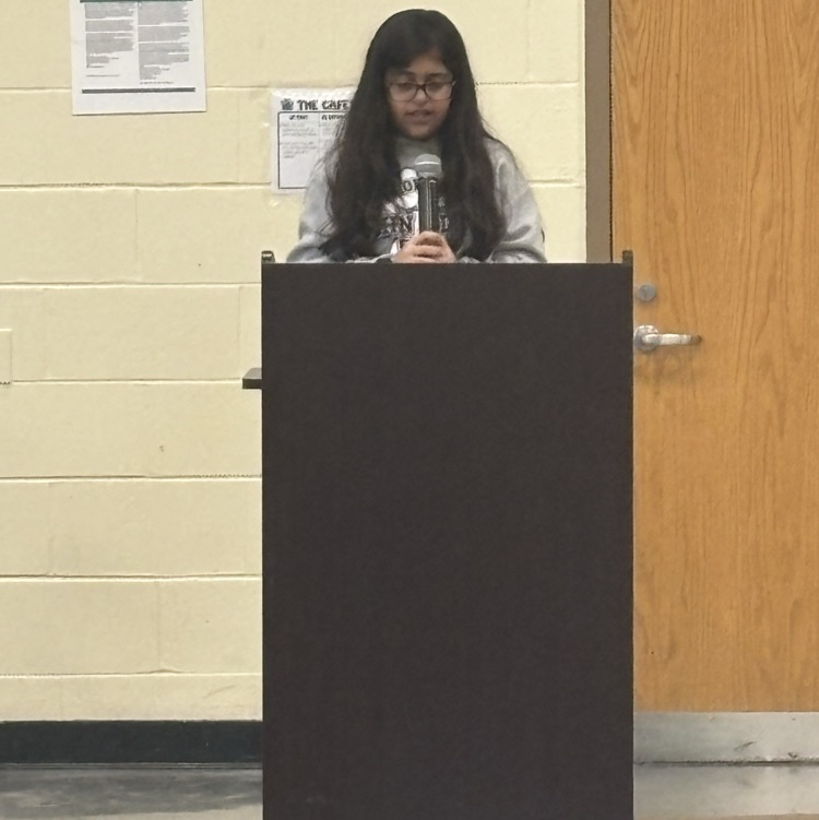 student speaking into a microphone behind a podium