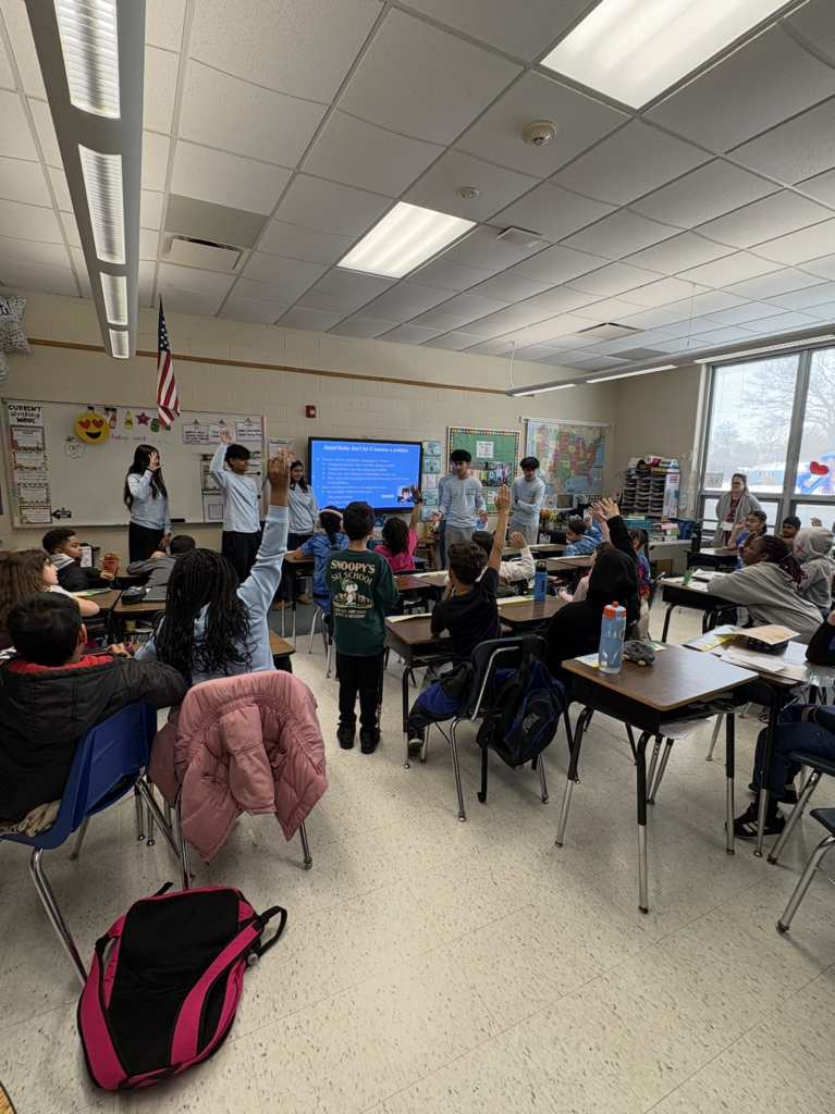 Students in classroom, raising hands