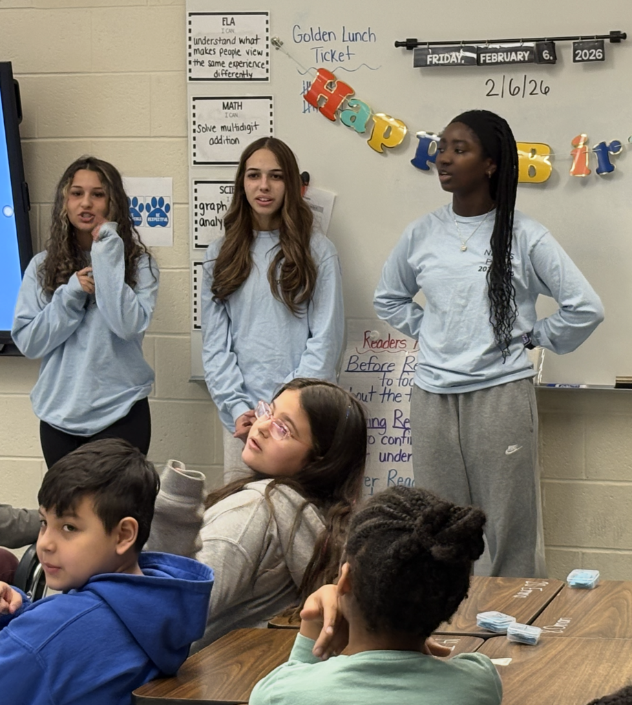Three high school students standing in blue shirts