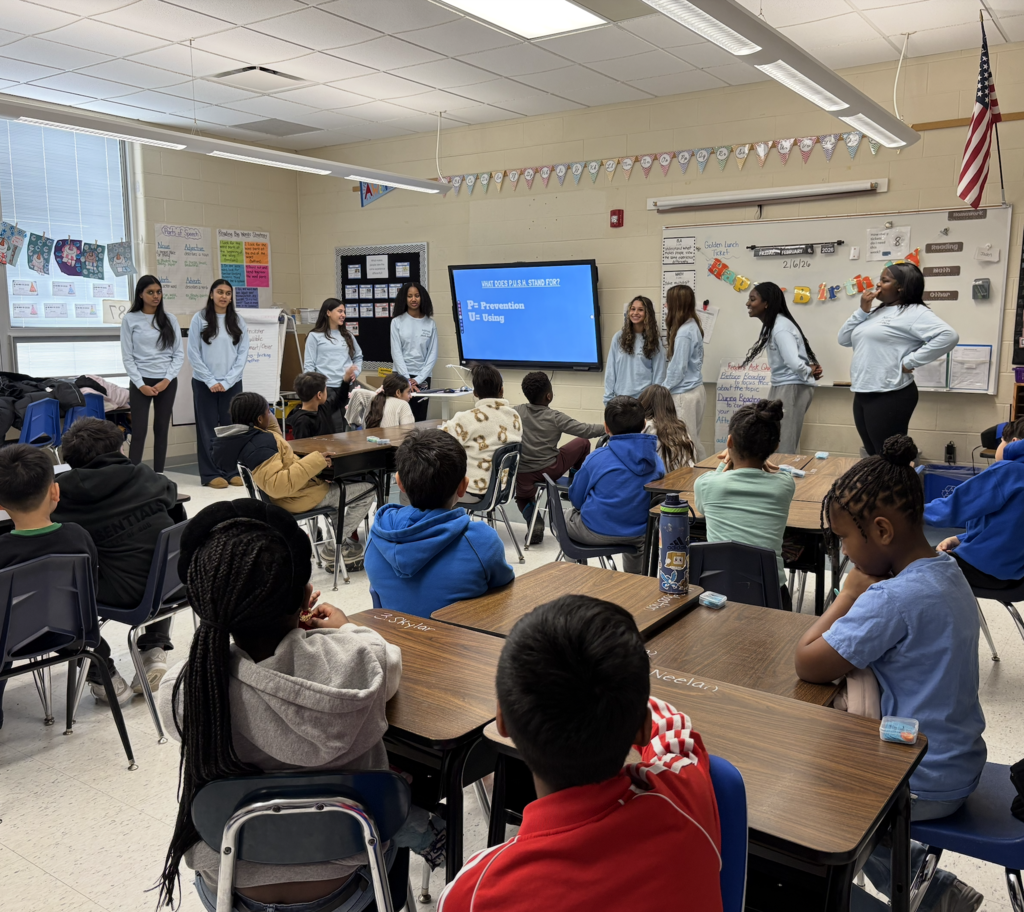 Students presenting in front of elementary students in classroom