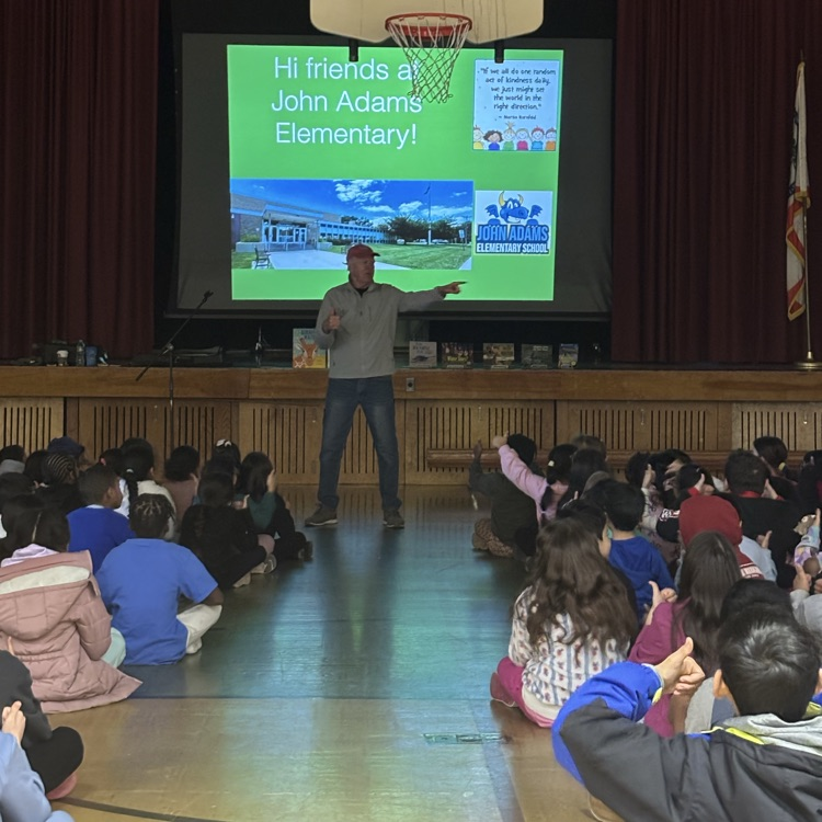 Man presenting to a group of students sitting on a gym floor