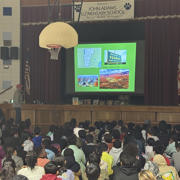 Man presenting to a group of students sitting on a gym floor