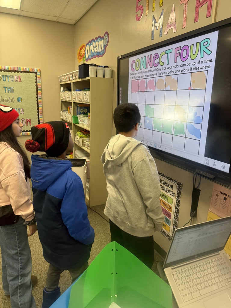Students playing connect four on an interactive white board with colored markers