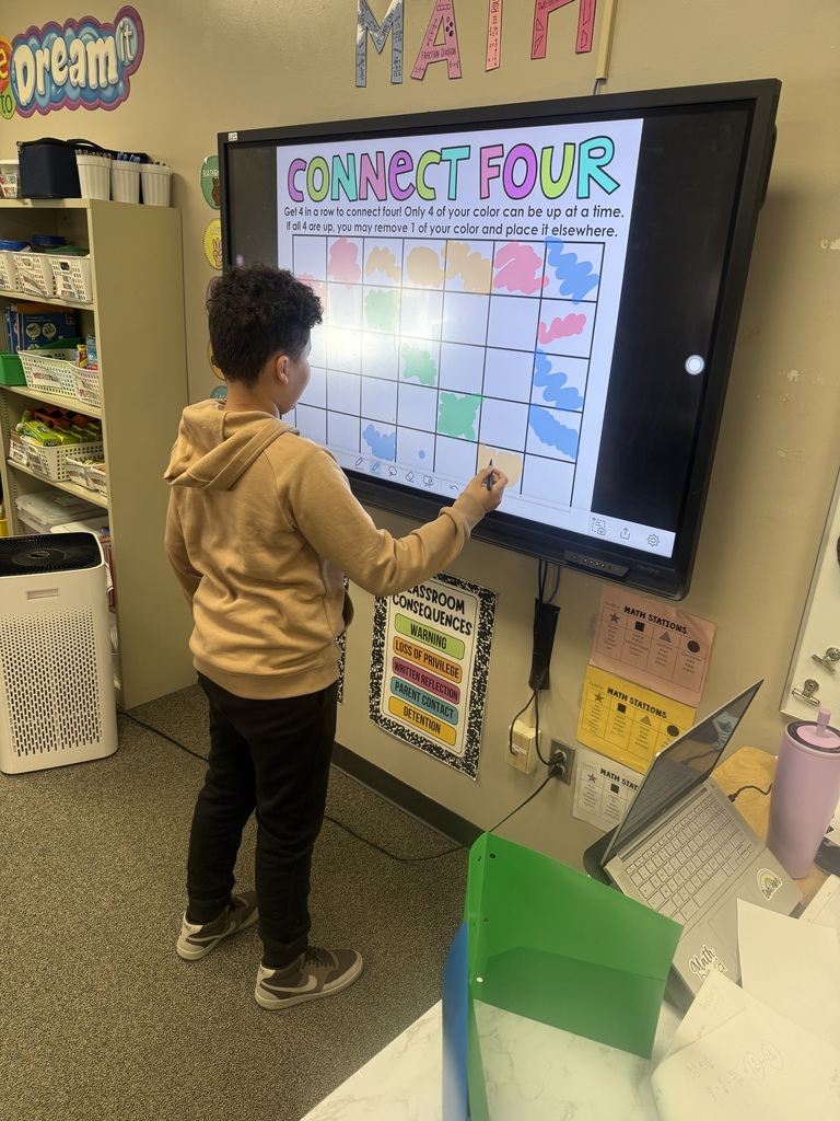 Students playing connect four on an interactive white board with colored markers