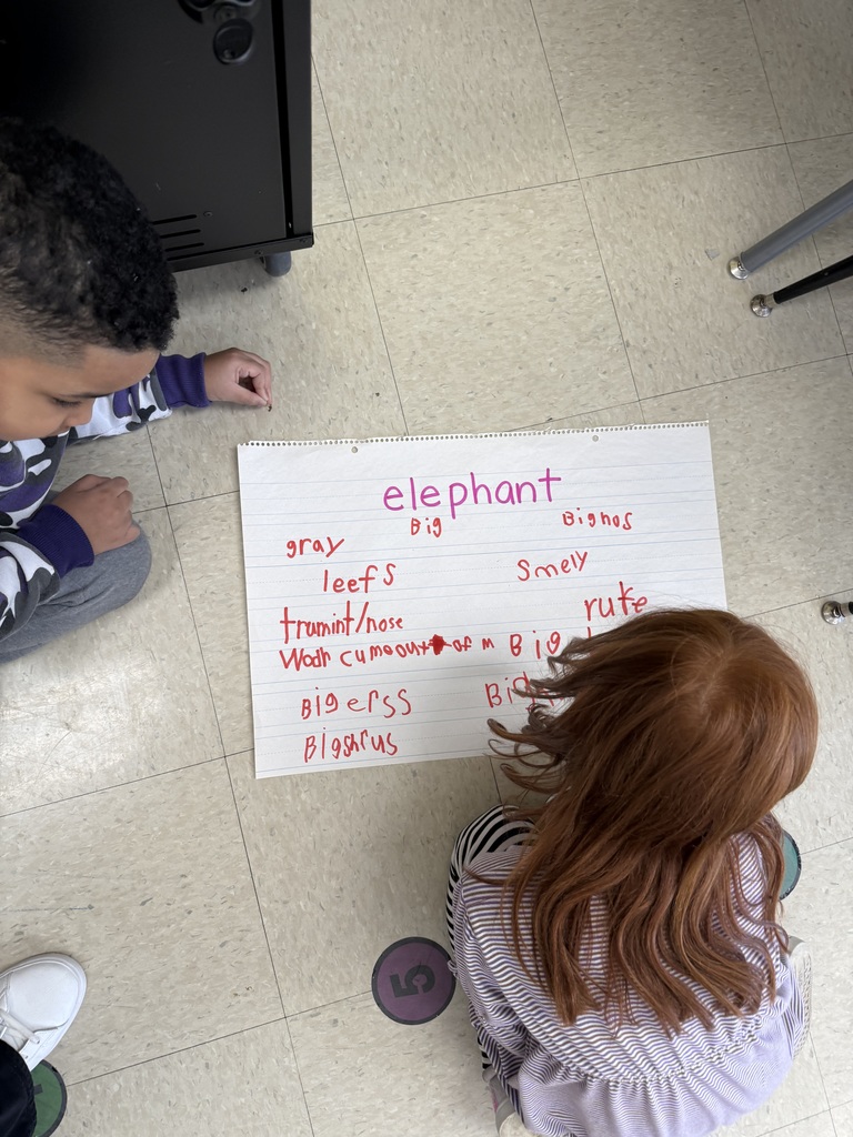 .Students working on poster board on the floor, writing words phonetically