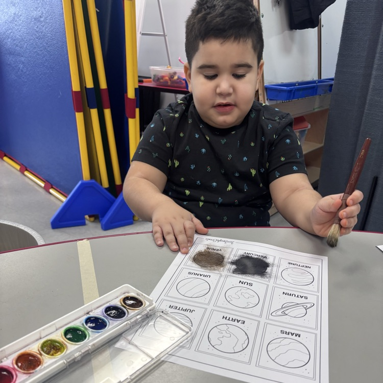 Preschool student painting at a table