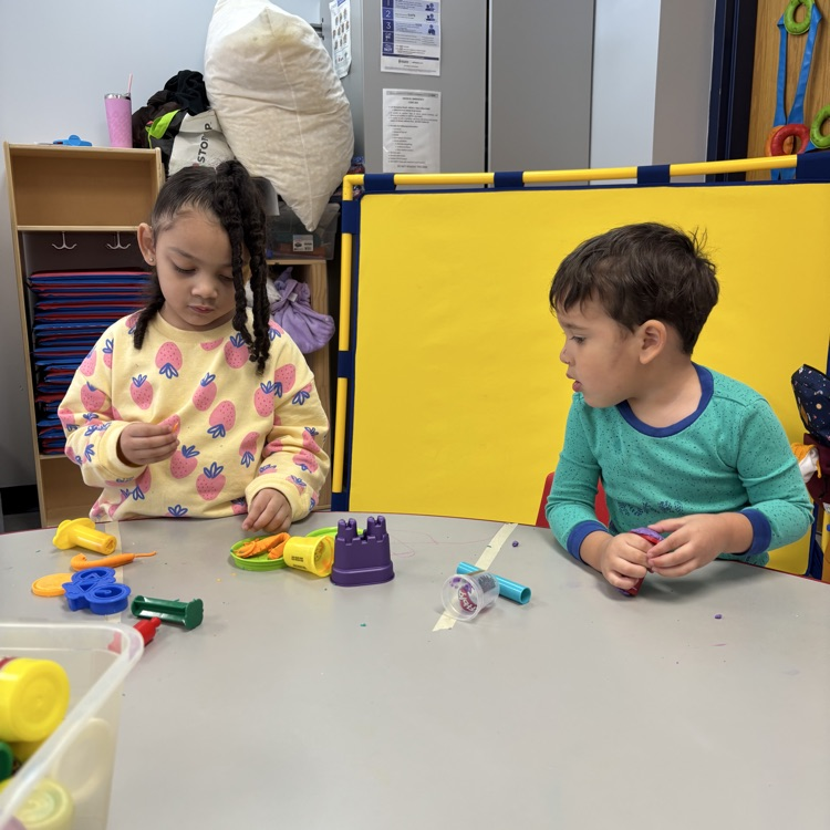 preschool students playing at table with toys