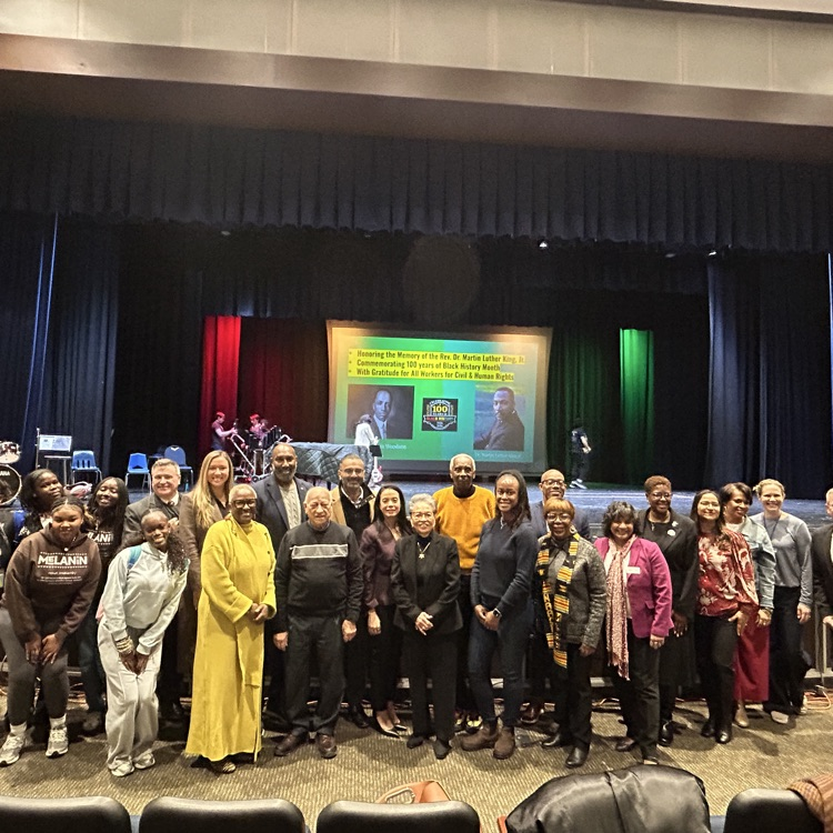 group of adults standing together in front of stage 