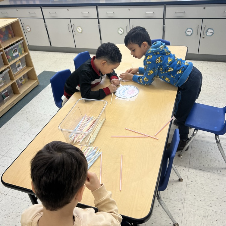 Students piecing together straws at a table