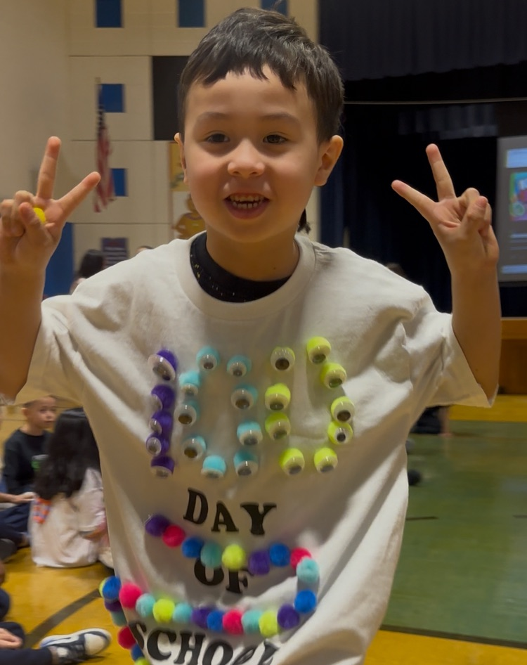 Students are posing at their kindergarten fashion show for the 100th day of school. 