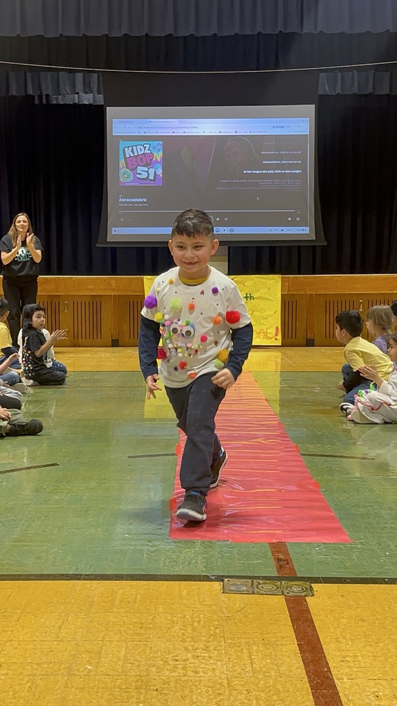 Students are posing at their kindergarten fashion show for the 100th day of school. 