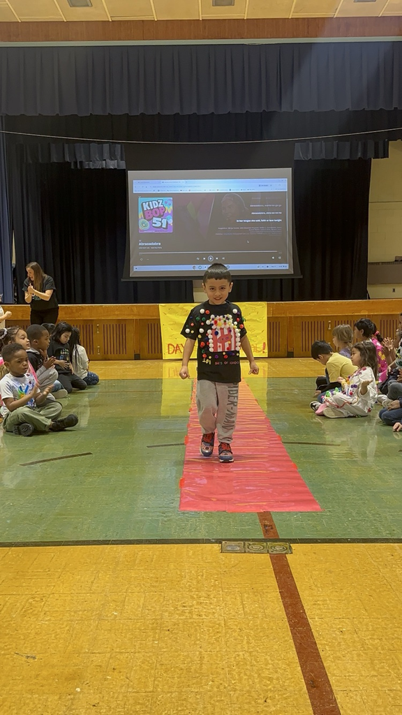 Students are posing at their kindergarten fashion show for the 100th day of school. 