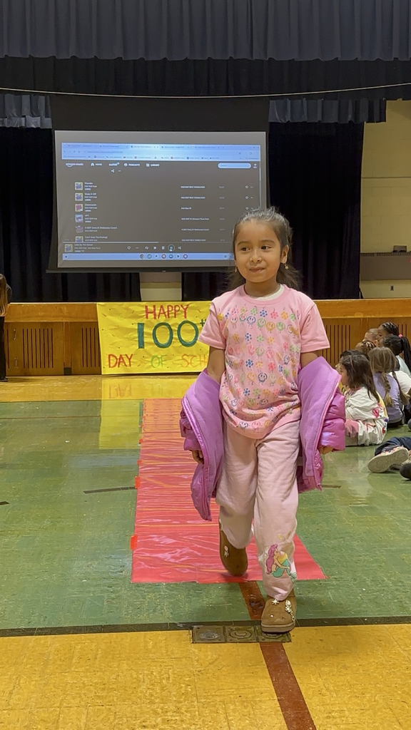 Students are posing at their kindergarten fashion show for the 100th day of school. 