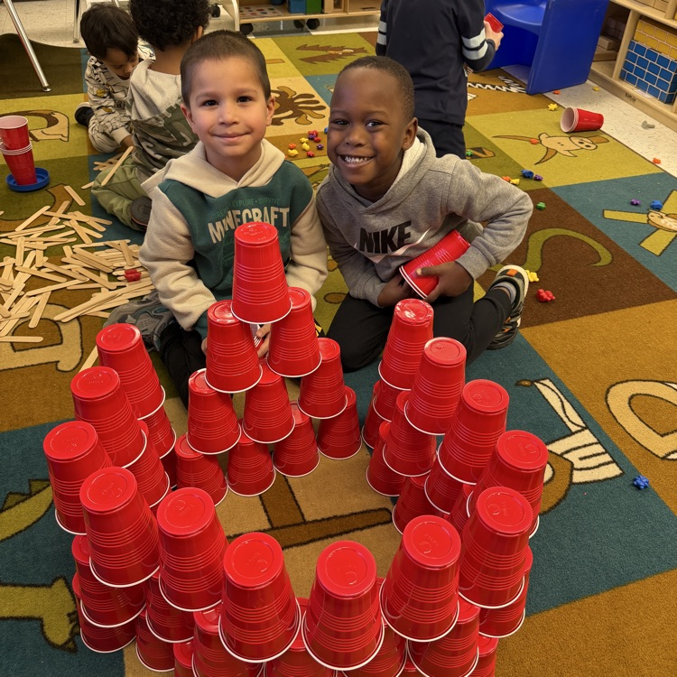 Students building with cups on the floor