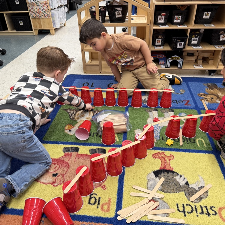 Students building with cups on the floor
