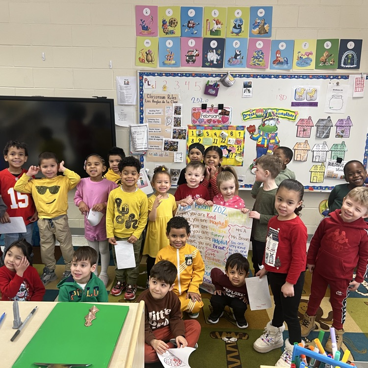 group of students in a classroom holding a poster
