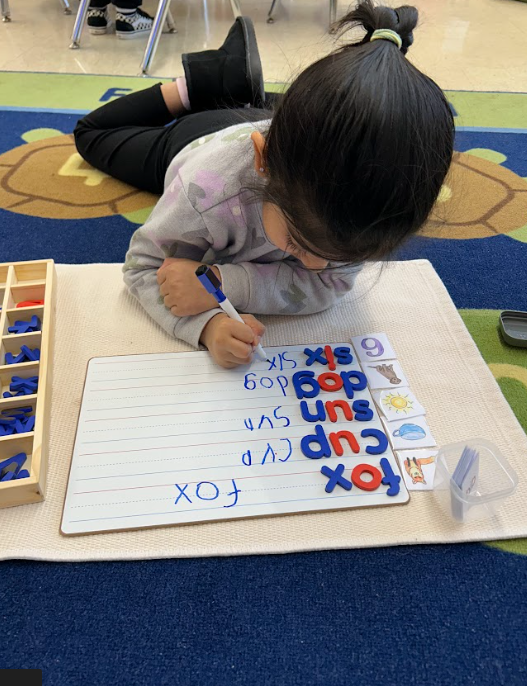 child writing on a dry erase board 