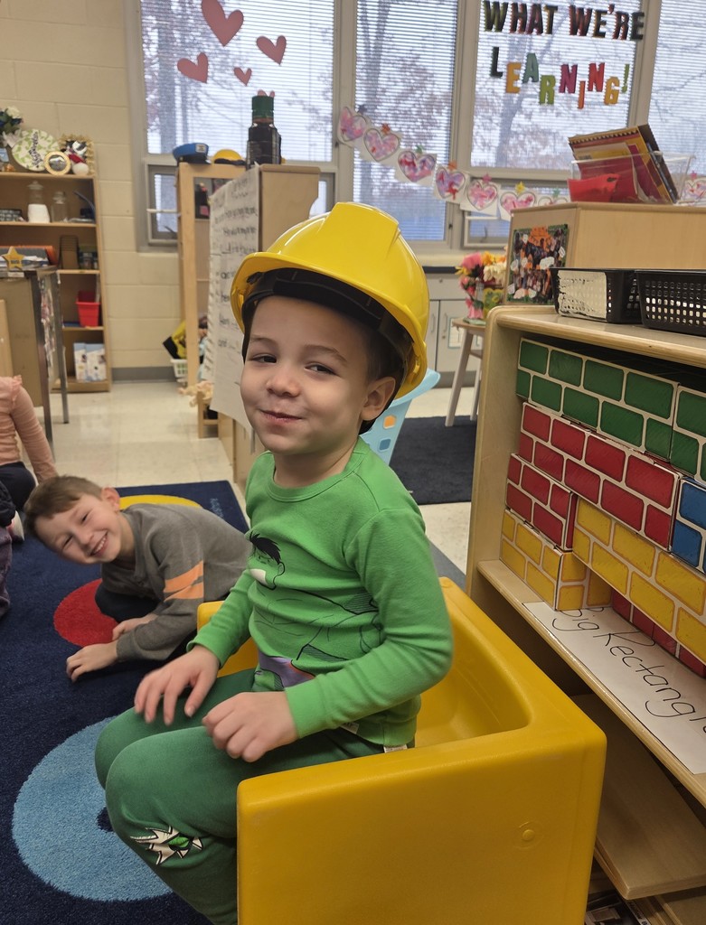 Kid wearing a construction hat inside of. classroom
