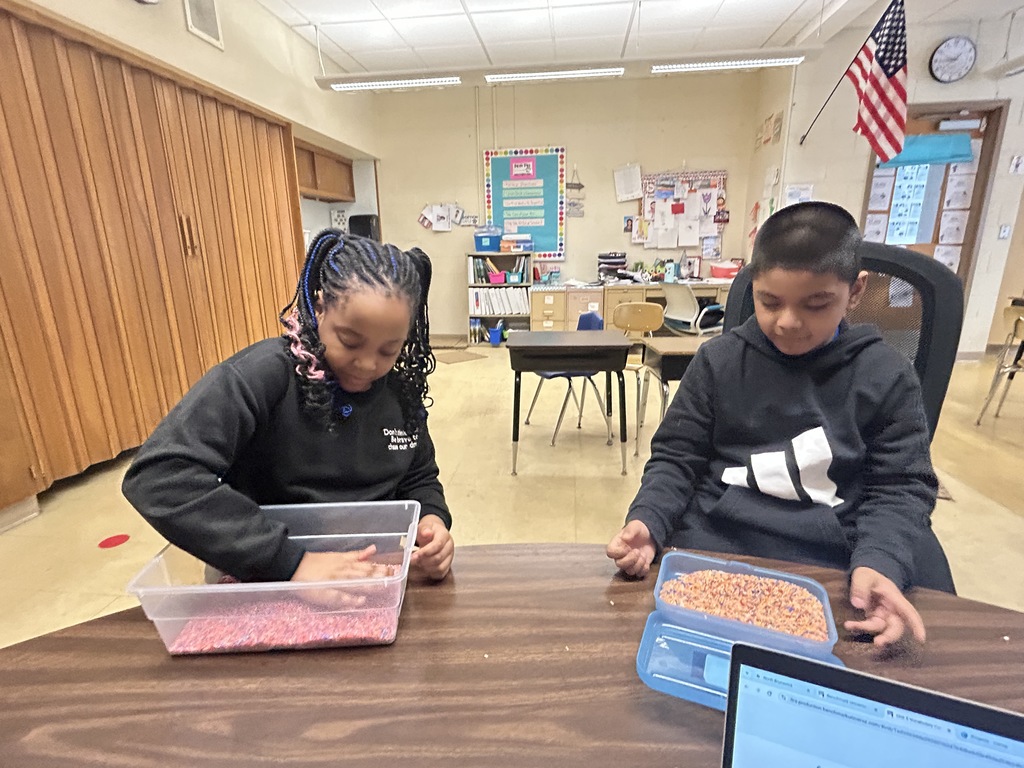 Students are using bins of rice to finger write letters