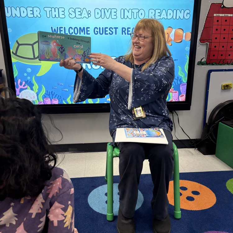 Adult reading a fish book to kids in a classroom