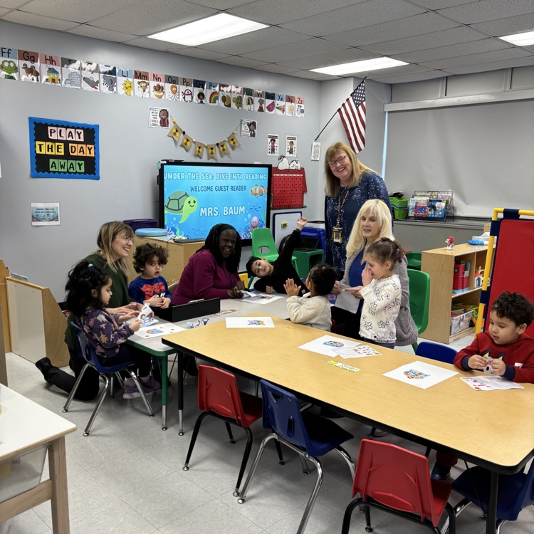 Students and teachers sitting at tables doing a craft