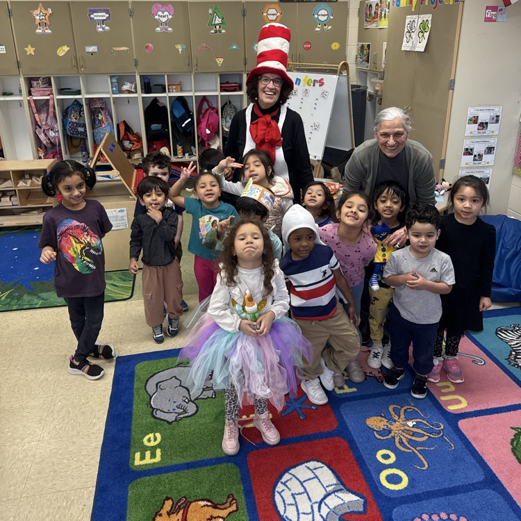 Students posing in a classroom with an adult dressed as cat in the hat
