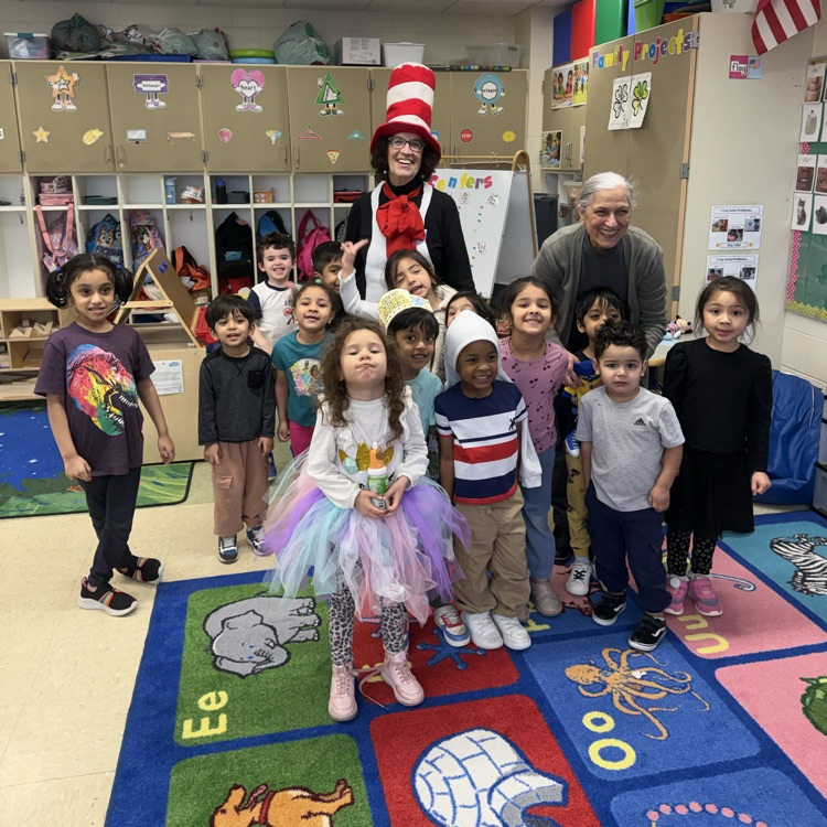 Students posing in a classroom with an adult dressed as cat in the hat