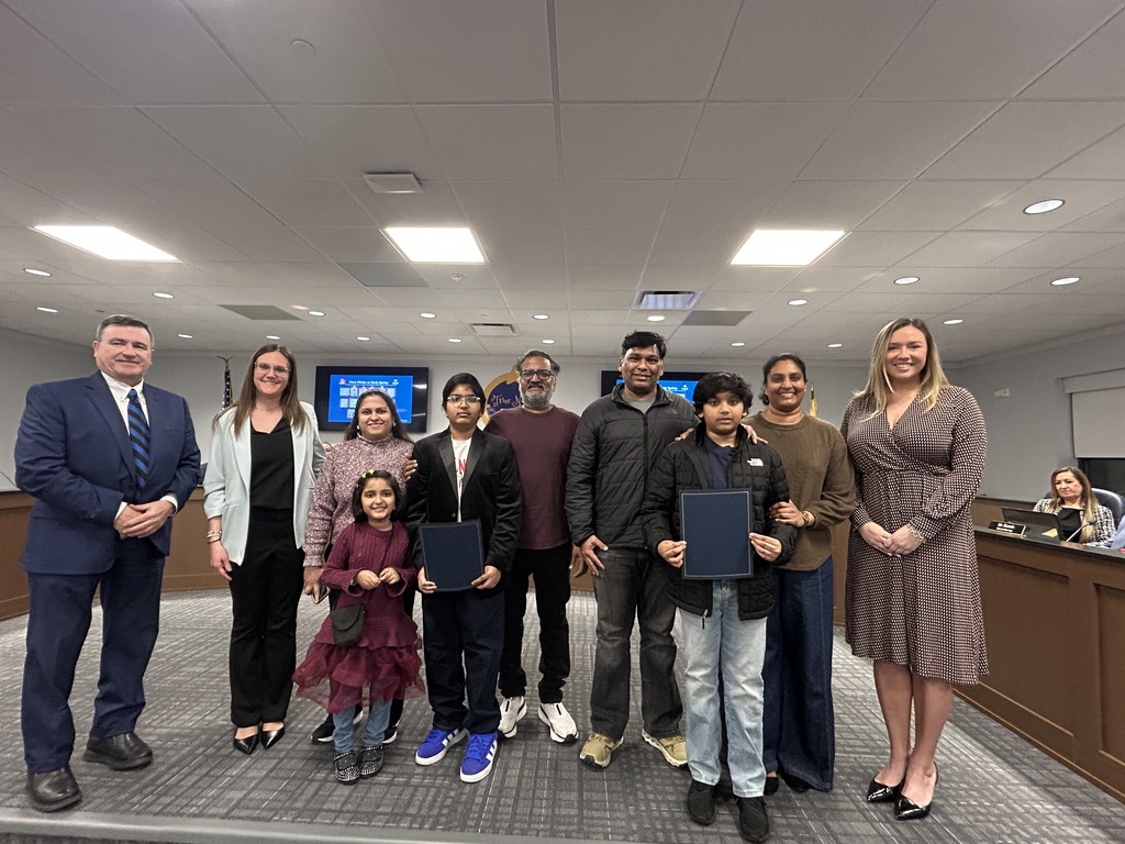 Students holding certificates posing with their families and staff members
