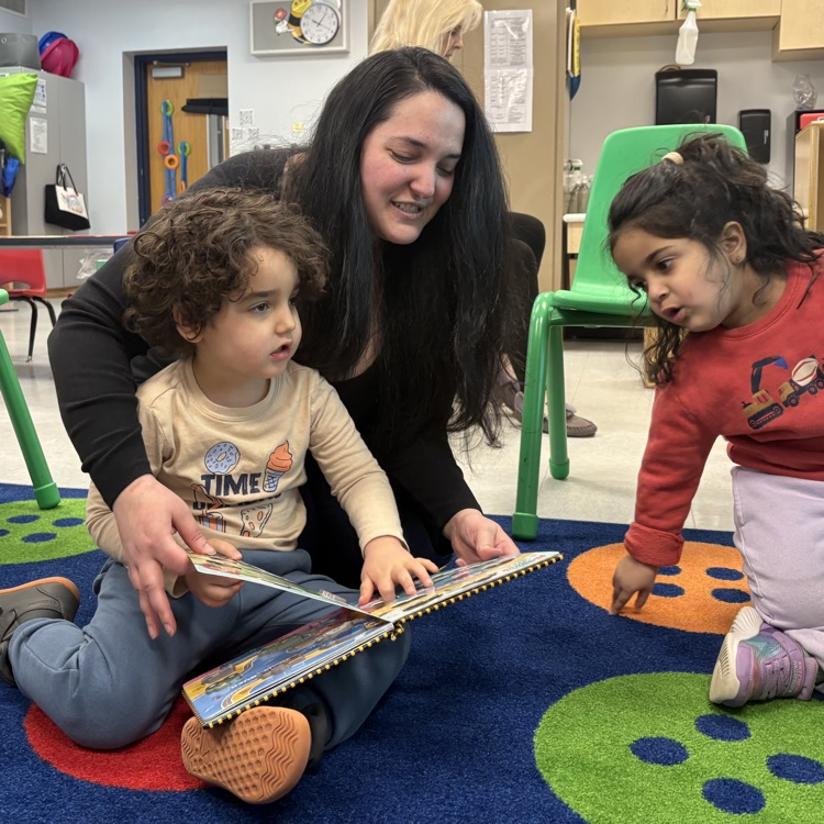 Students and teacher reading book on carpet