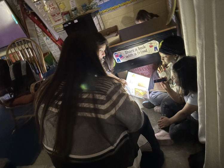 Students reading with their parents with flashlights in the classroom
