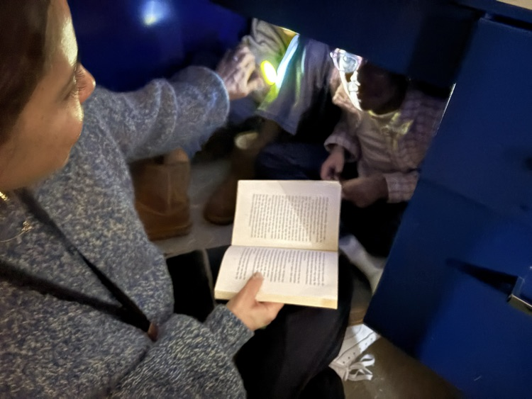readingStudents reading with their parents with flashlights in the classroom