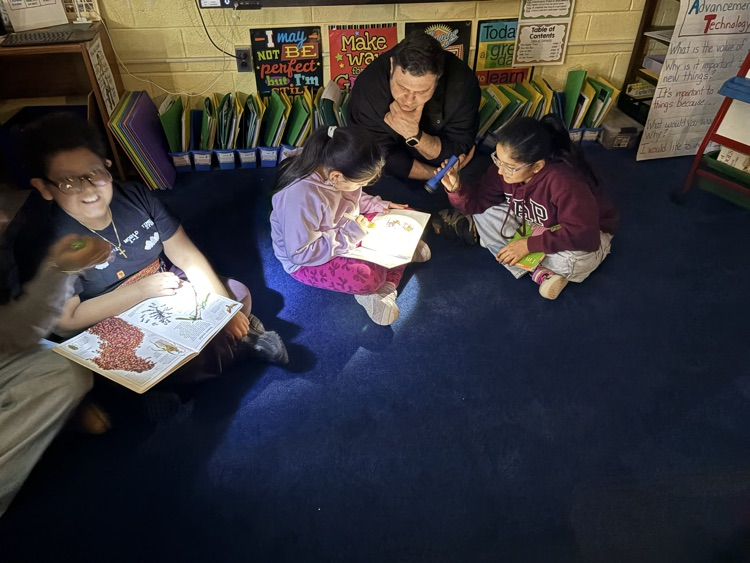 Students reading with their parents with flashlights in the classroom