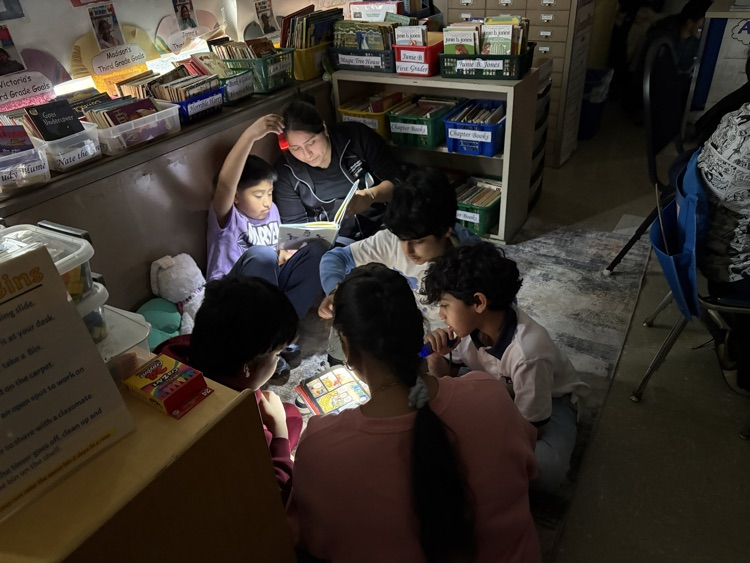 Students reading with their parents with flashlights in the classroom