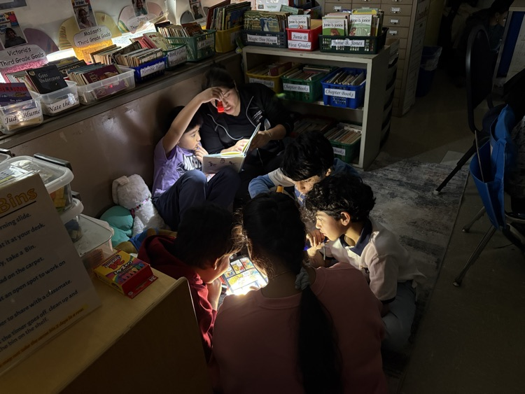 Students reading with their parents with flashlights in the classroom 