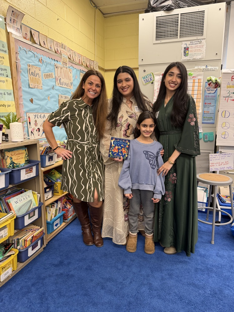 Three adults and a student posing together with a book
