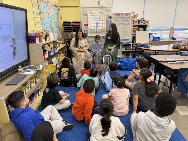 Students listening to an adult reader in their classroom