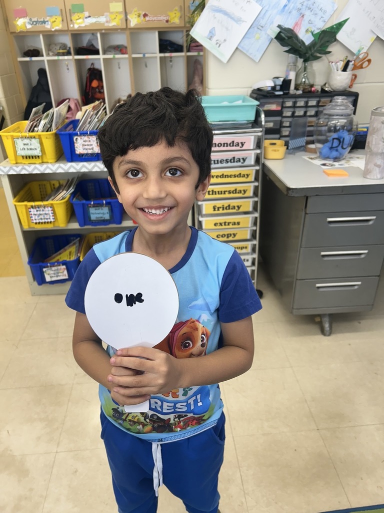 a student smiling and holding a dry erase board with the word "one"