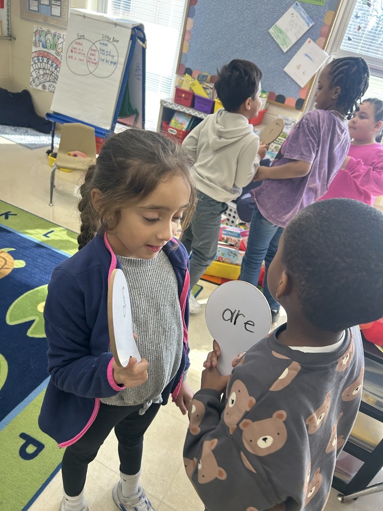 two students showing each other their dry erase boards with sight words written
