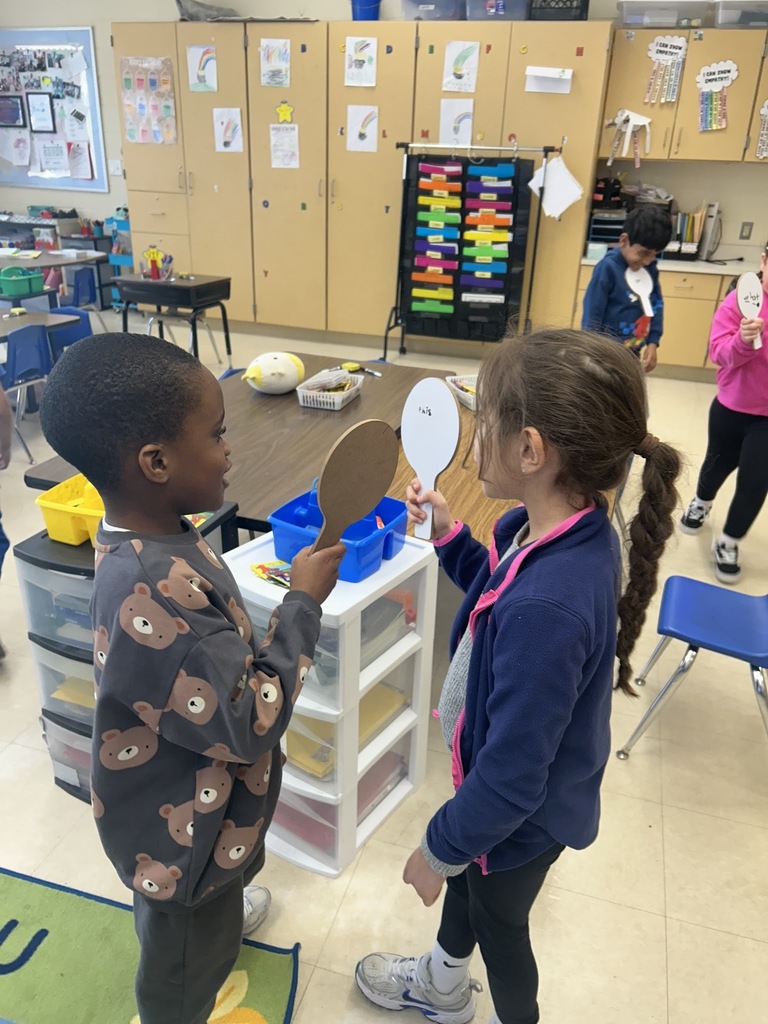 two students showing each other their dry erase boards with sight words written