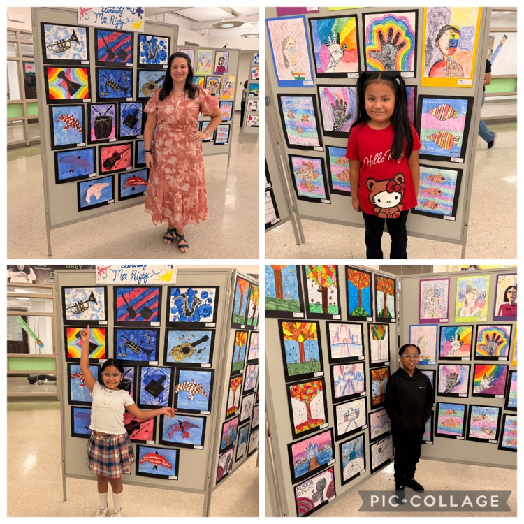 Students posing with paintings on display