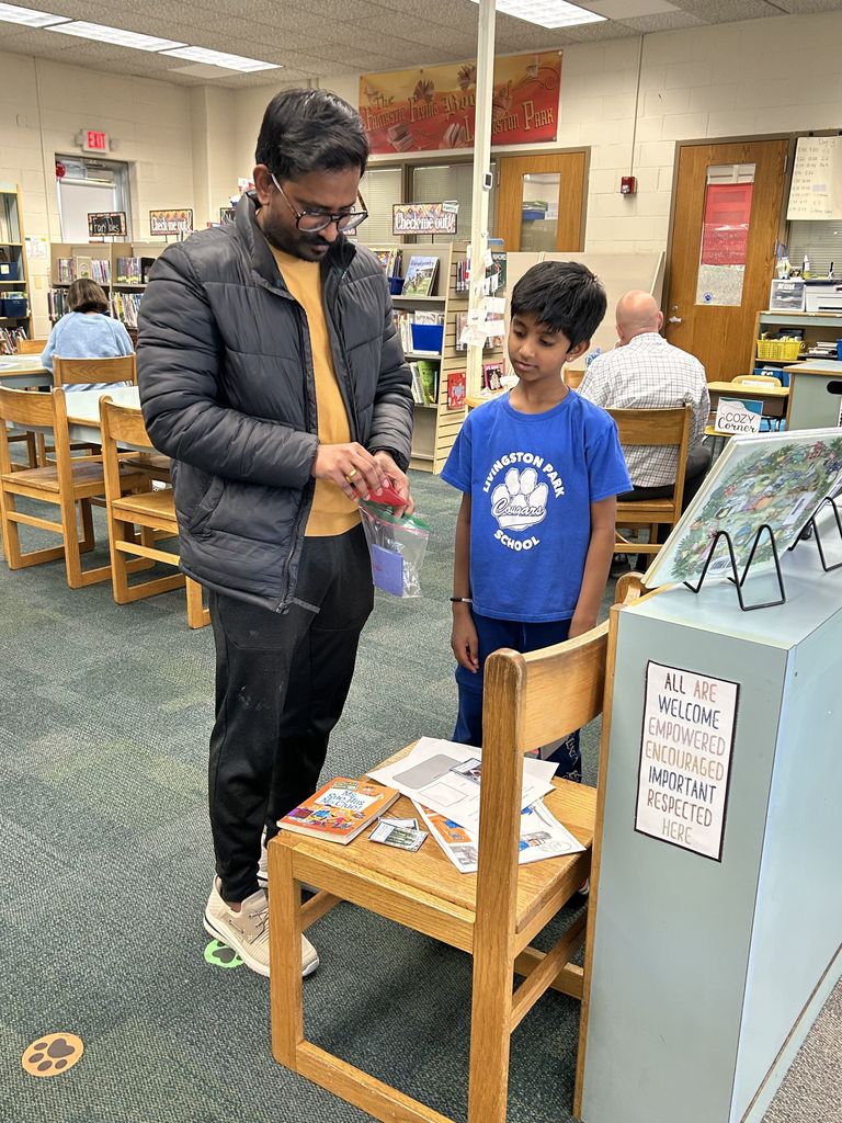 Student shares project with adult in classroom library