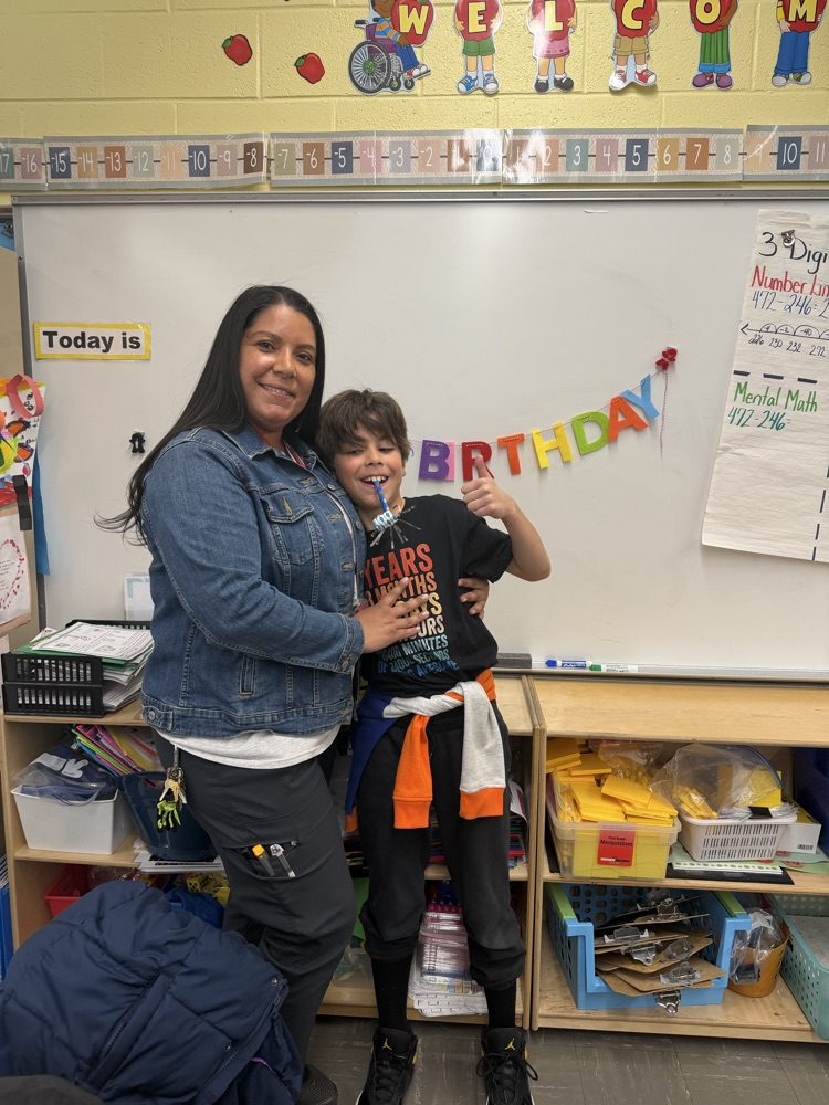 Adult and student posing together in a classroom